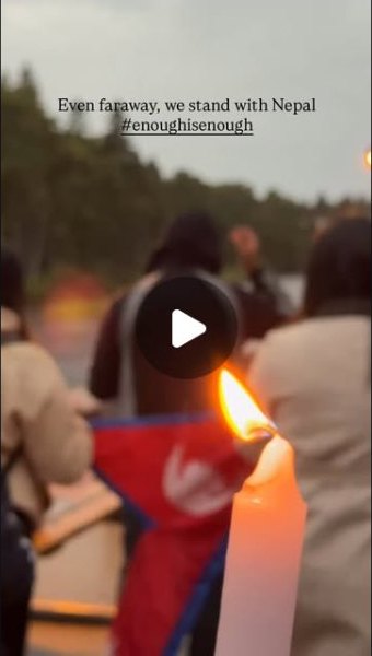 Candles burning beside a Nepali flag at an evening gathering, with the words Even faraway, we stand with Nepal.